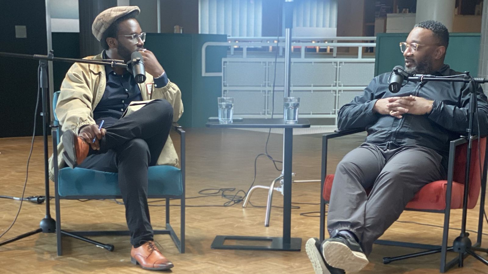 Opname van De Tafel van Utrecht Podcast: presentator en gast aan tafel met microfoons, camera op de voorgrond